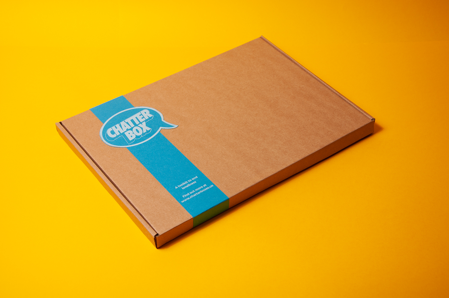 A photograph of a brown cardboard box with a blue band around one end. The band has a speech bubble shaped logo reading Chatterbox. The box is sitting on a yellow background.