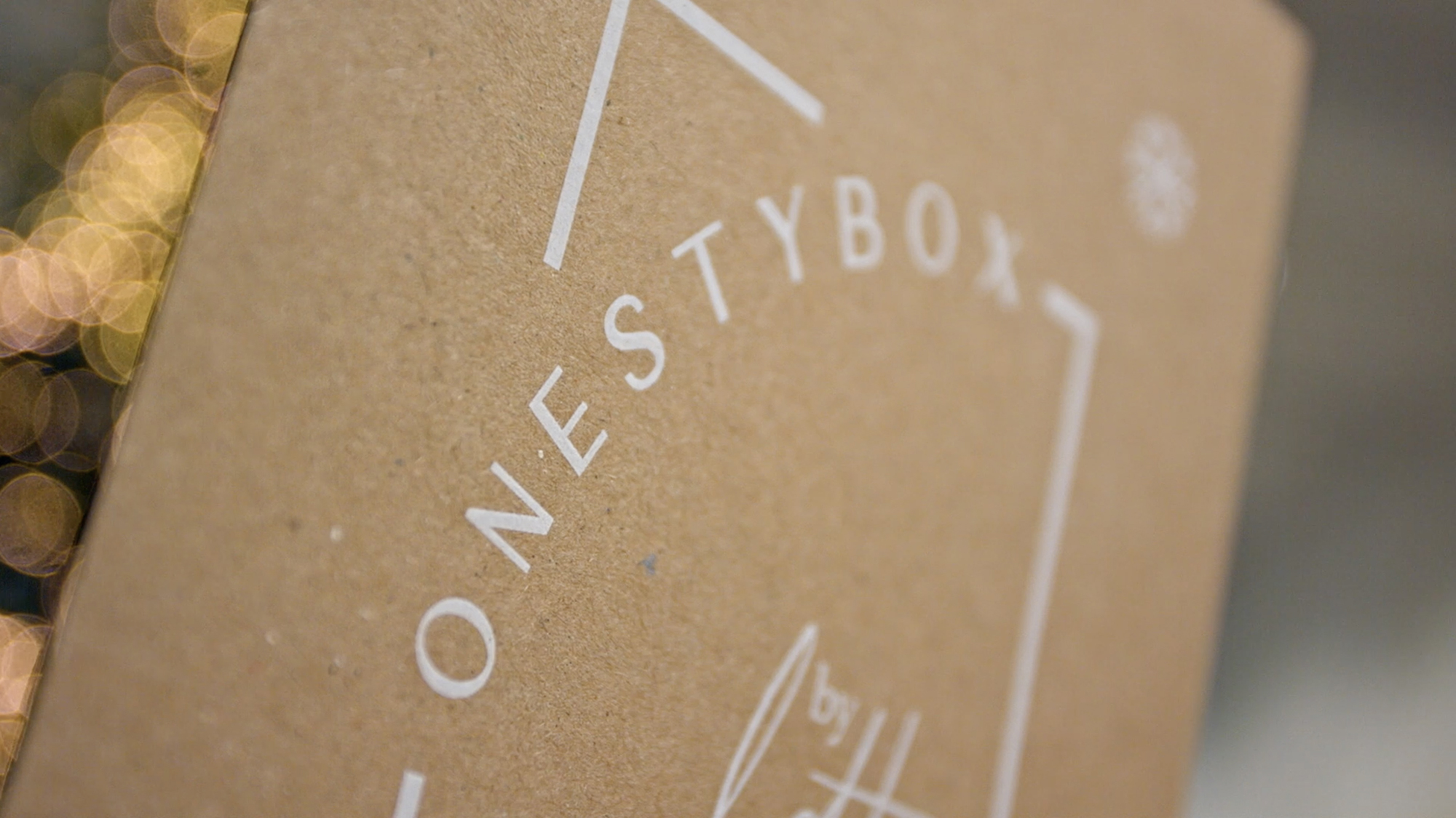 A close up photograph of the onestybox logo, printed in white toner on a brown, environmentally friendly Kraft paper booklet
